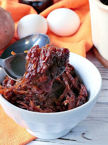 A spoon with some Grated Sweet Potato Pudding.