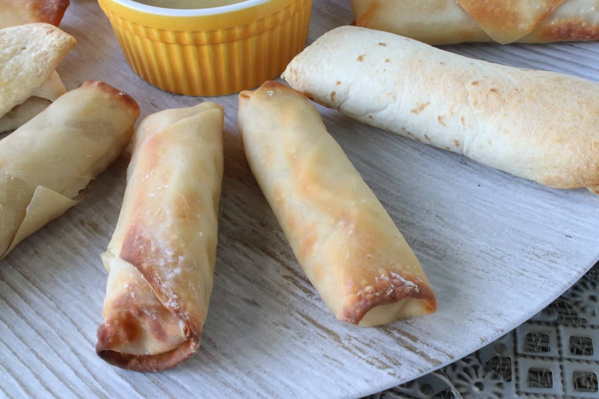 Golden brown Ham and Cheese Eggrolls on a round platter.