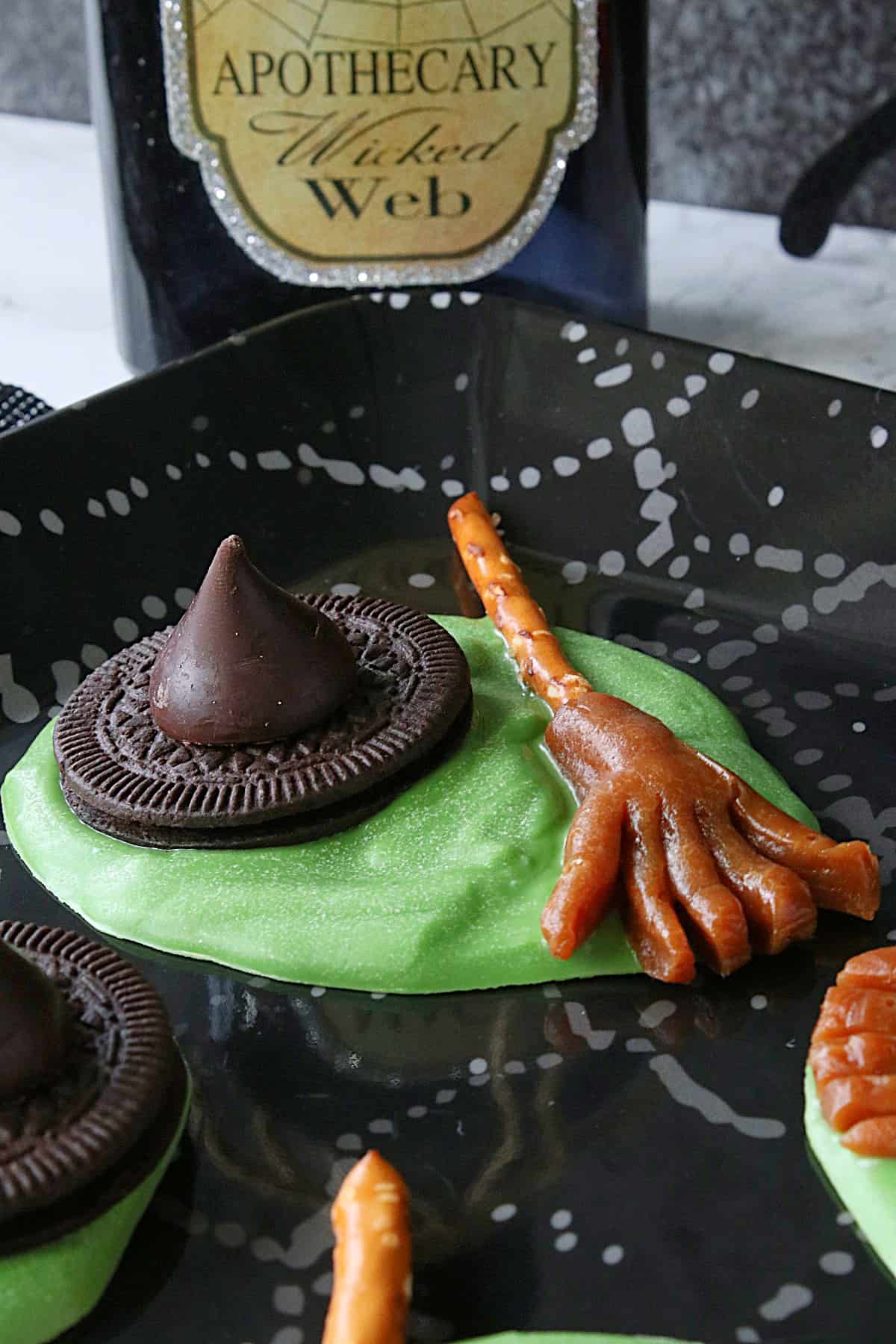 A green Melted Witch Candy with a pretzel and caramel broom stick.