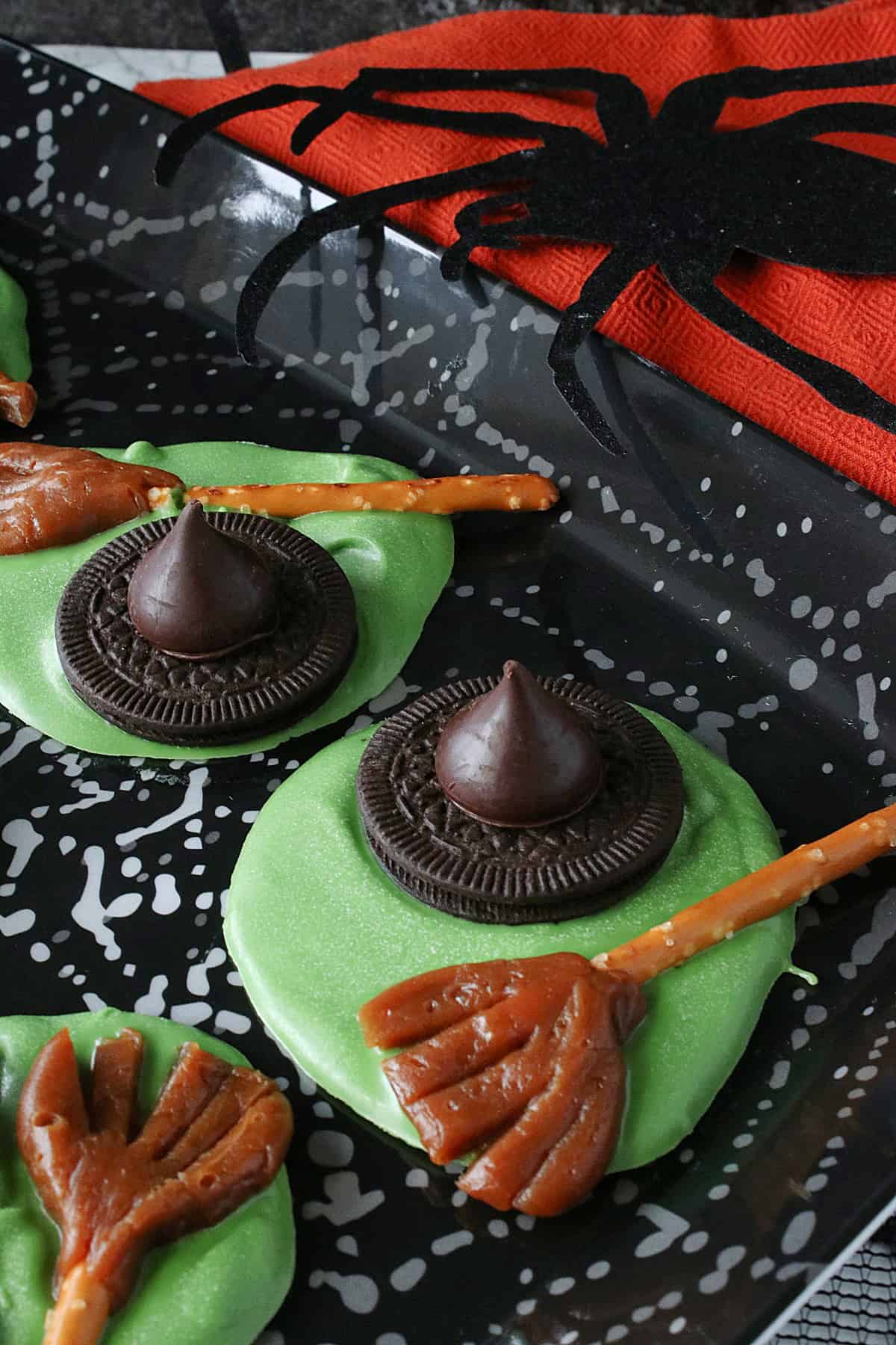 Three green Melted Witch Candy on a black plate with a spider.