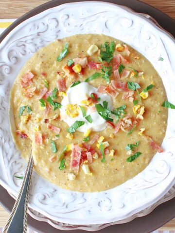A white bowl filled with Roasted Corn and Potato Chowder with bacon on top.