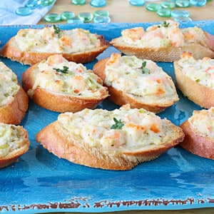 Shrimp Rangoon Garlic Toasts on a bright blue platter with thyme sprigs on top.