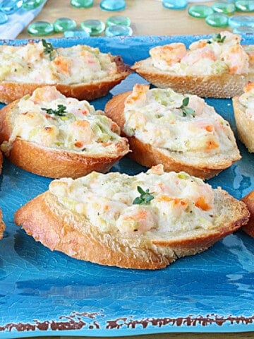 Shrimp Rangoon Garlic Toasts on a bright blue platter with thyme sprigs on top.
