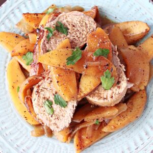 Slices of Pork Tenderloin with Cinnamon Apples and parsley on a plate.