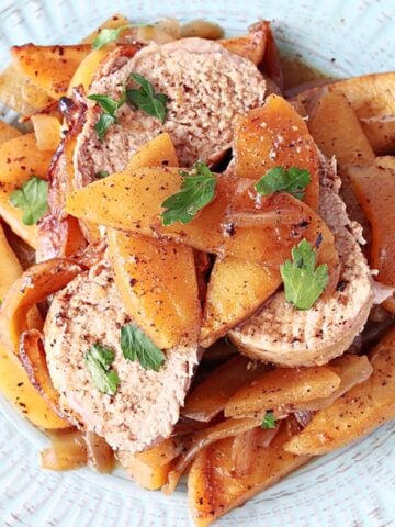 Slices of Pork Tenderloin with Cinnamon Apples and parsley on a plate.