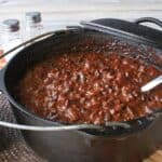 A black Dutch oven with Molé Turkey Chili inside and a serving ladle.