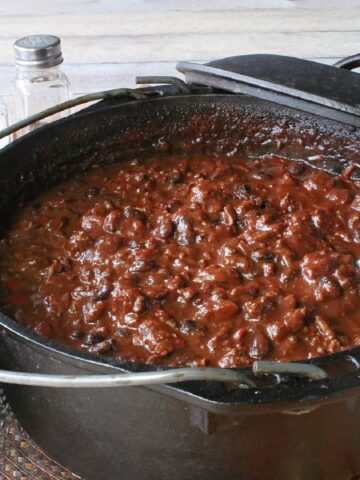 A black Dutch oven with Molé Turkey Chili inside and a serving ladle.