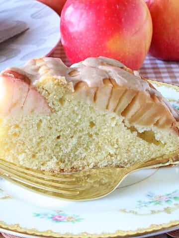 A slice of German Sunken Apple Cake on a pretty plate with a fork.