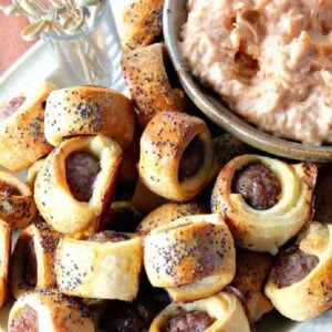 A pile of Bratwurst Bite Appetizers on a plate with poppy seeds on top.