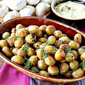 A brown bowl filled with Roasted Baby Potatoes with Garlic and Herbs.