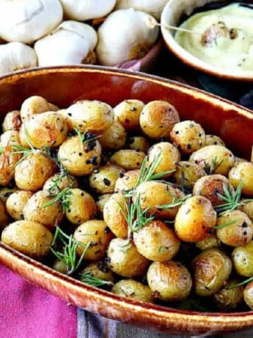 A brown bowl filled with Roasted Baby Potatoes with Garlic and Herbs.