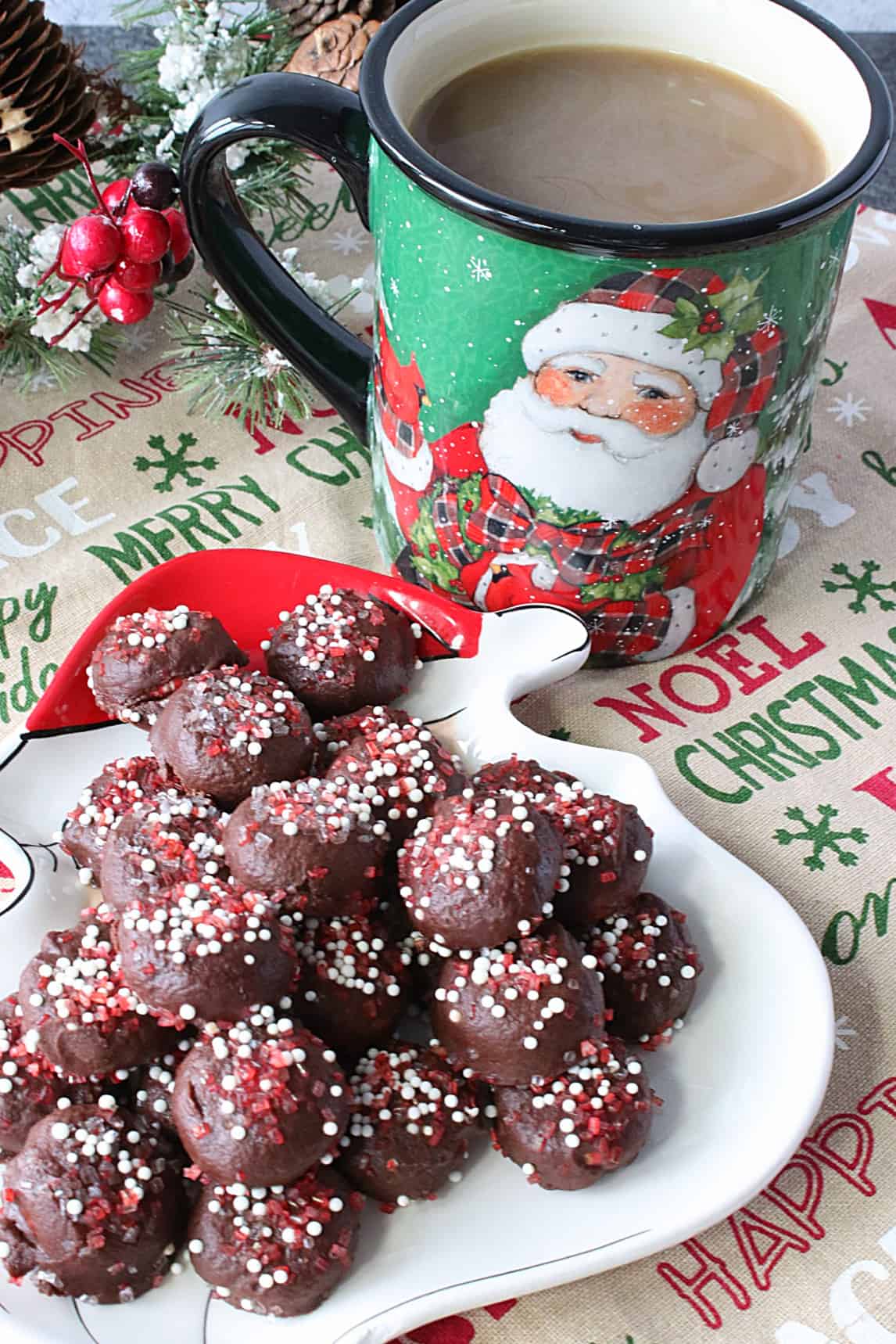 A Christmas plate filled with Chocolate Peppermint Coffee Drops with a cup of coffee in the background.