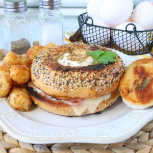 An Egg in the Hole Breakfast Sandwich with melted cheese and tater tots on the side.