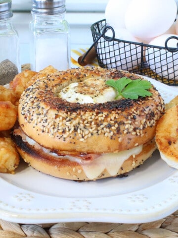 An Egg in the Hole Breakfast Sandwich with melted cheese and tater tots on the side.