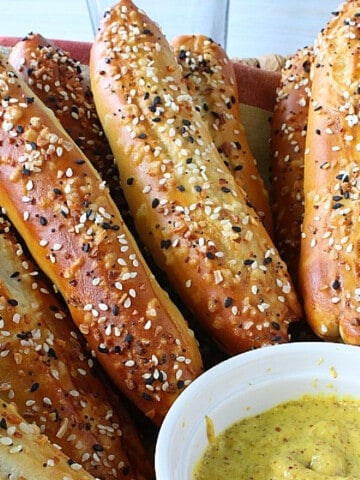 Soft Pretzel Rods sprinkled with everything seasoning along with a dish of mustard.