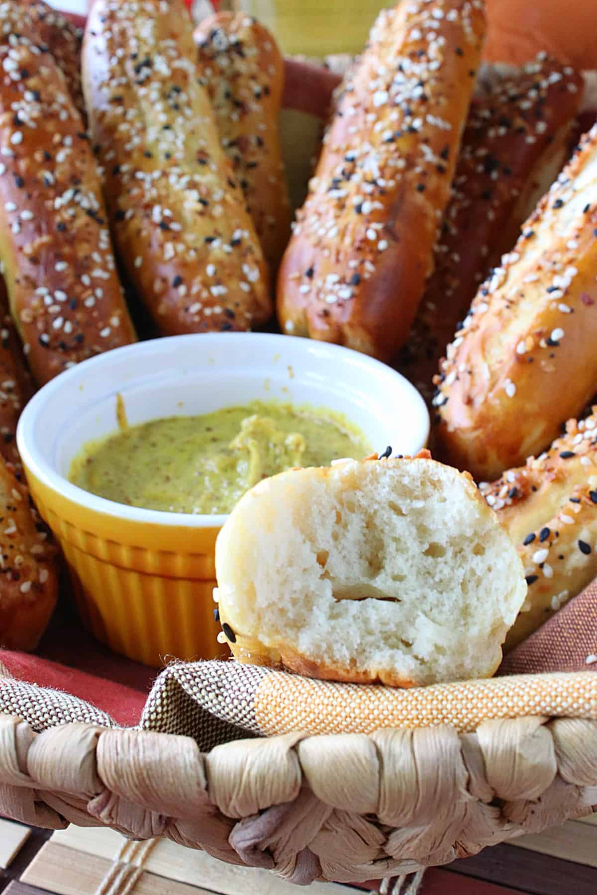 A closeup of the inside of a Soft Pretzel Rod with a bit taken out and a bowl of mustard.