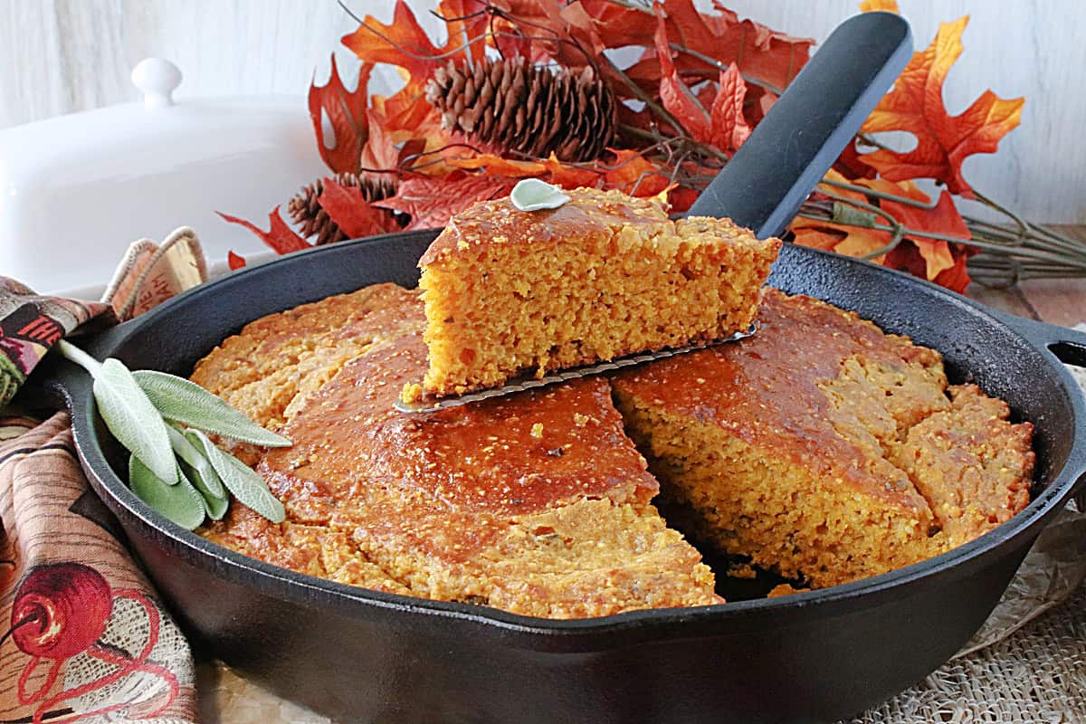 A cast iron skillet filled with beautifully golden Pumpkin Cornbread with Sage.