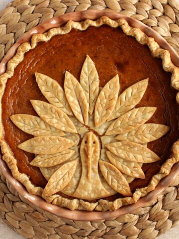 An adorable Turkey Crust Pumpkin Pie on a rattan placemat.