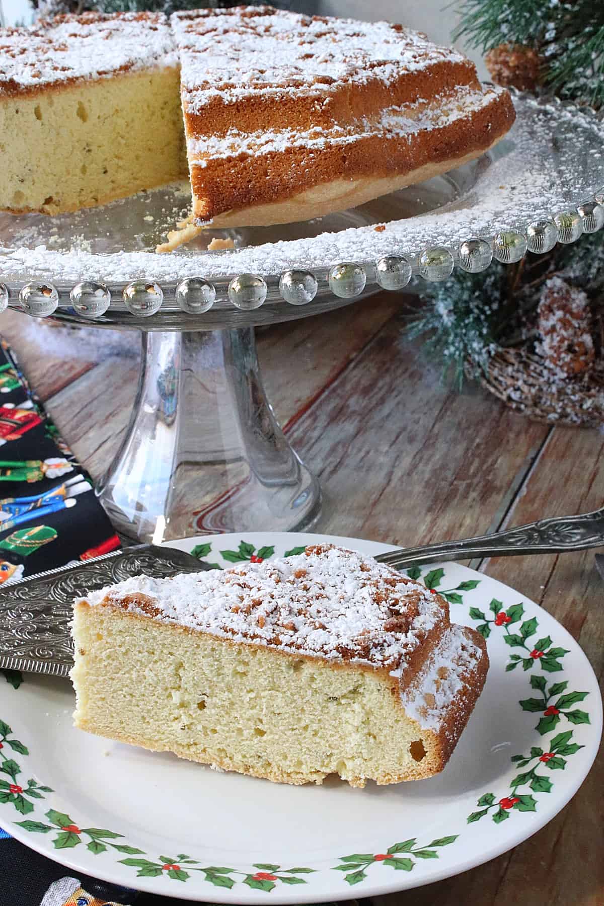 A slice of Anise Cookie Bars on a Christmas plate with a cake stand and the remaining cookie bars in the background.
