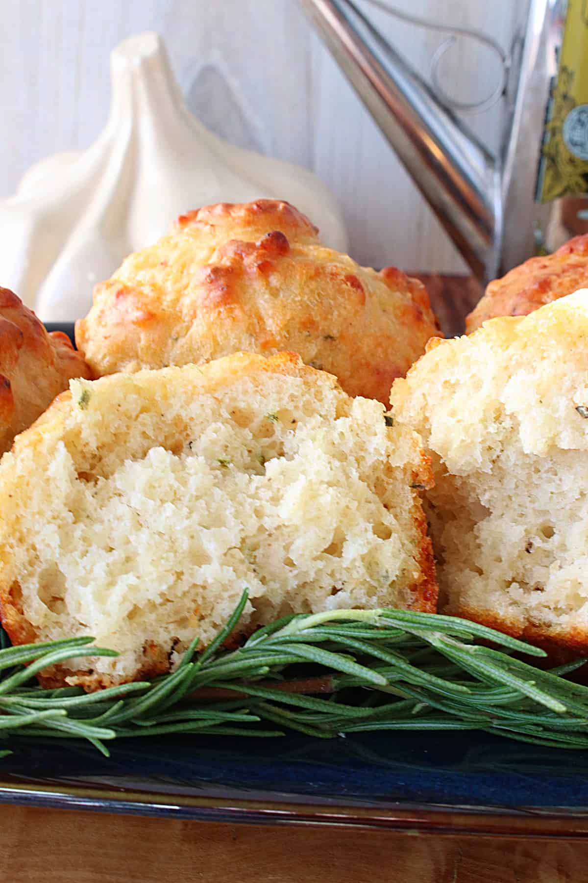 The inside of a Garli Rosemary Focaccia Muffin with a sprig of rosemary in the forefront.