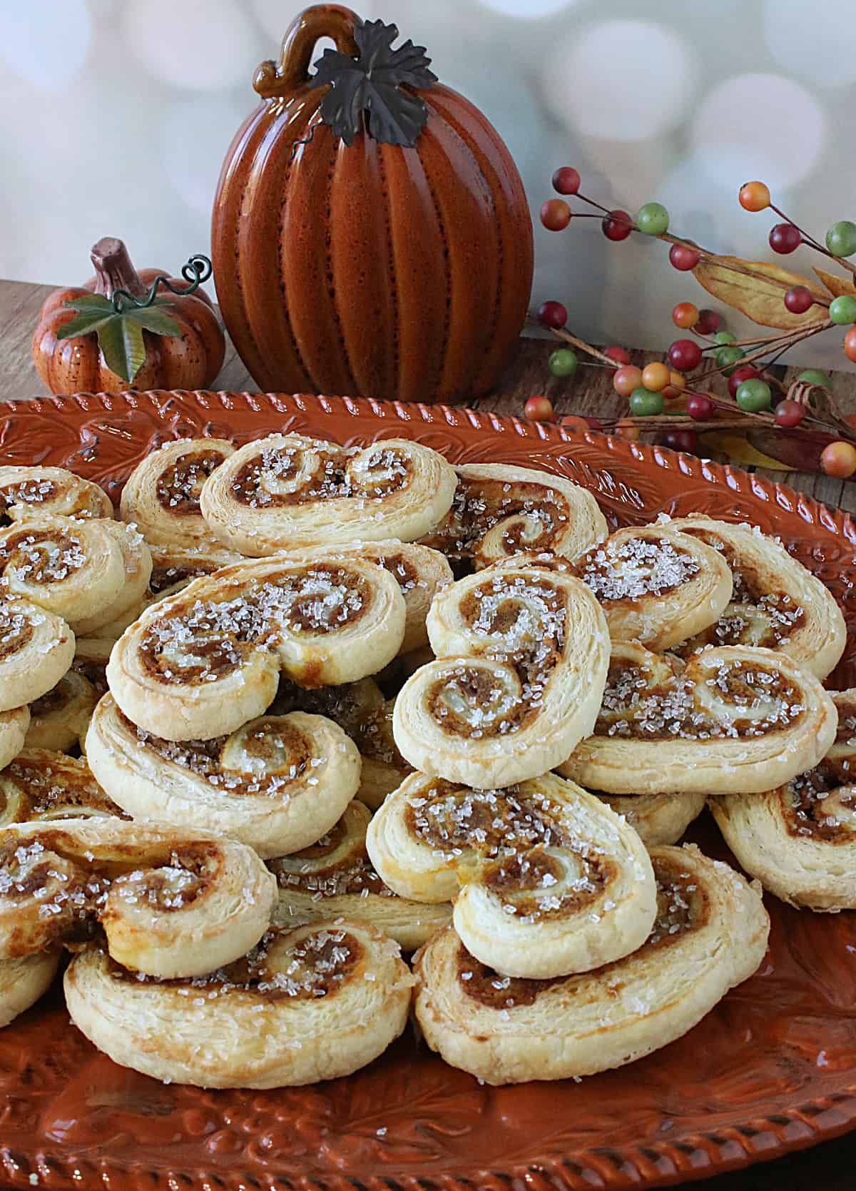 An orange plate filled with Pumpkin Spice Palmiers topped with sanding sugar.