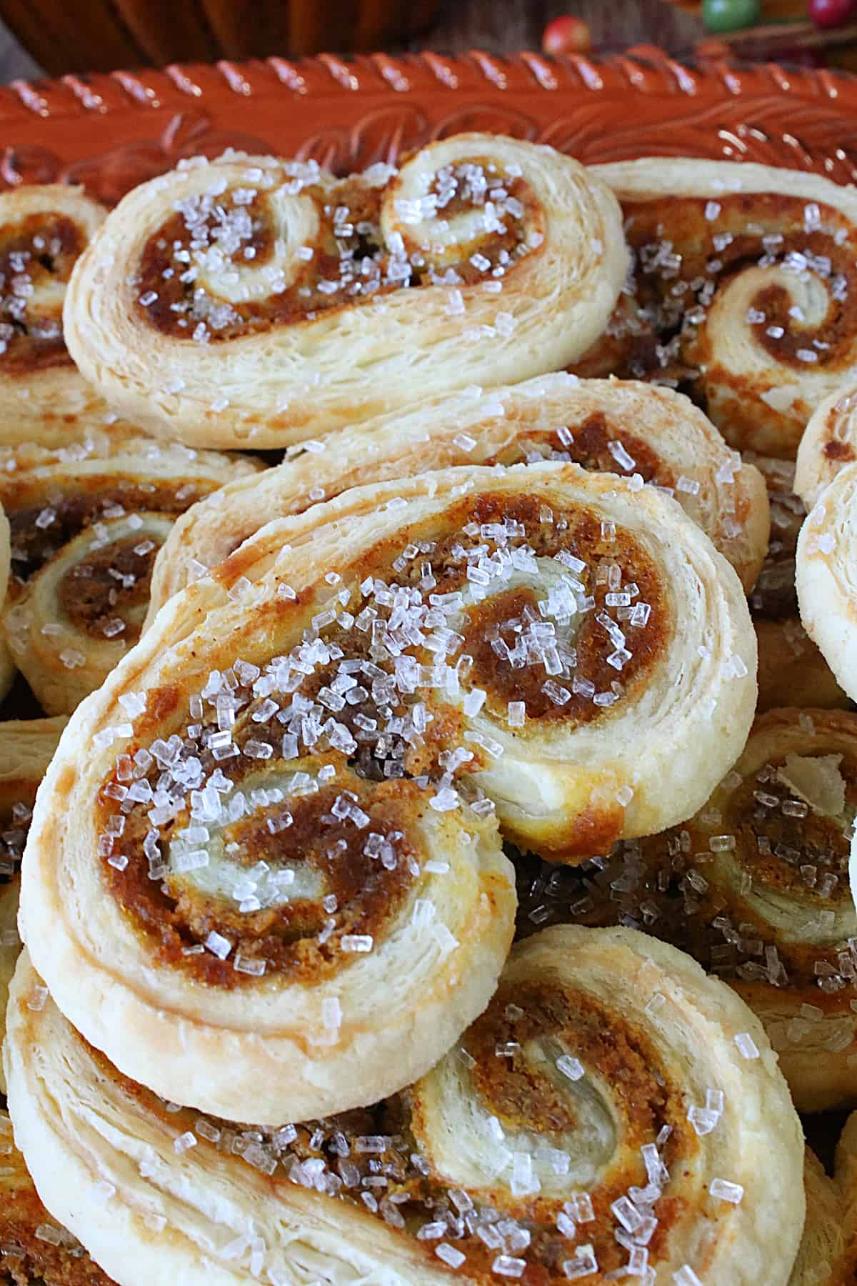 A closeup photo of a bunch of Pumpkin Spice Palmiers with sanding sugar on a platter.