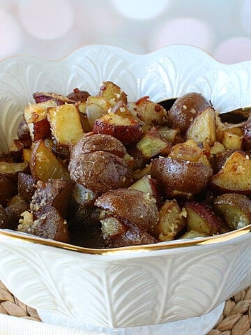 A pretty white bowl filled with Roasted Potatoes with Onion and Parmesan.