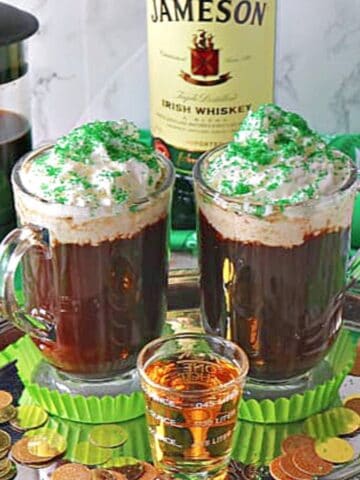 Two mugs of Traditional Irish Coffee on a silver tray with a shot of whiskey in the center.