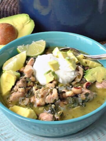 A bowl of black-eyed pea chicken chili with avocado and sour cream.