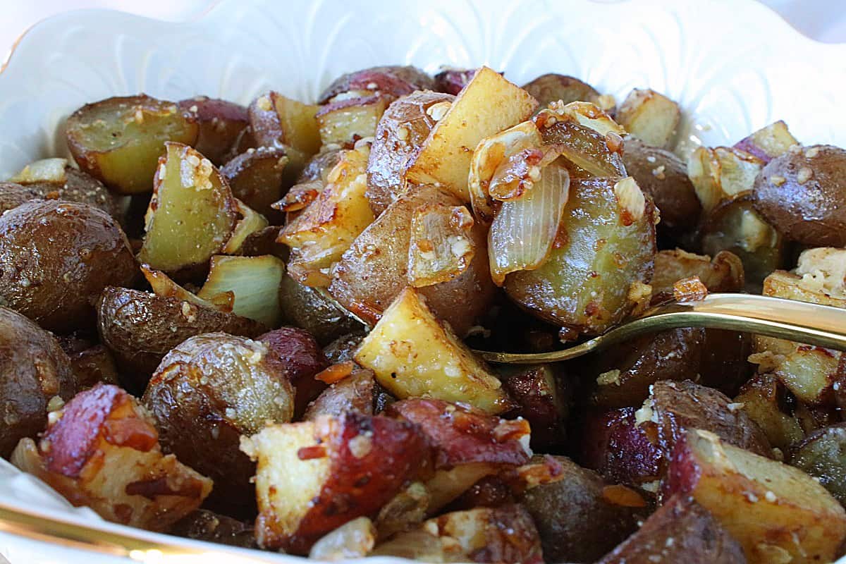 A closeup of a spoonful of Roasted Potatoes with Onions and Parmesan.