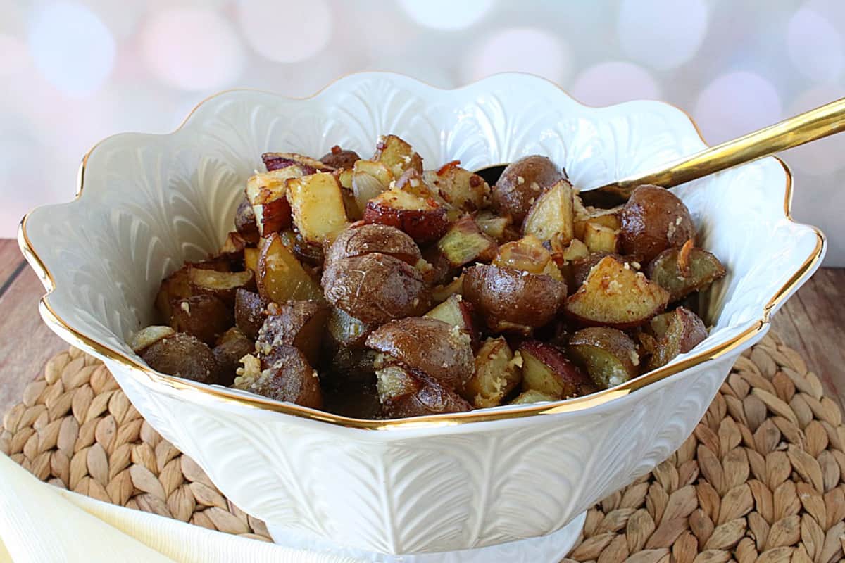 A pretty white bowl filled with Roasted Potatoes with Onions and Rosemary.