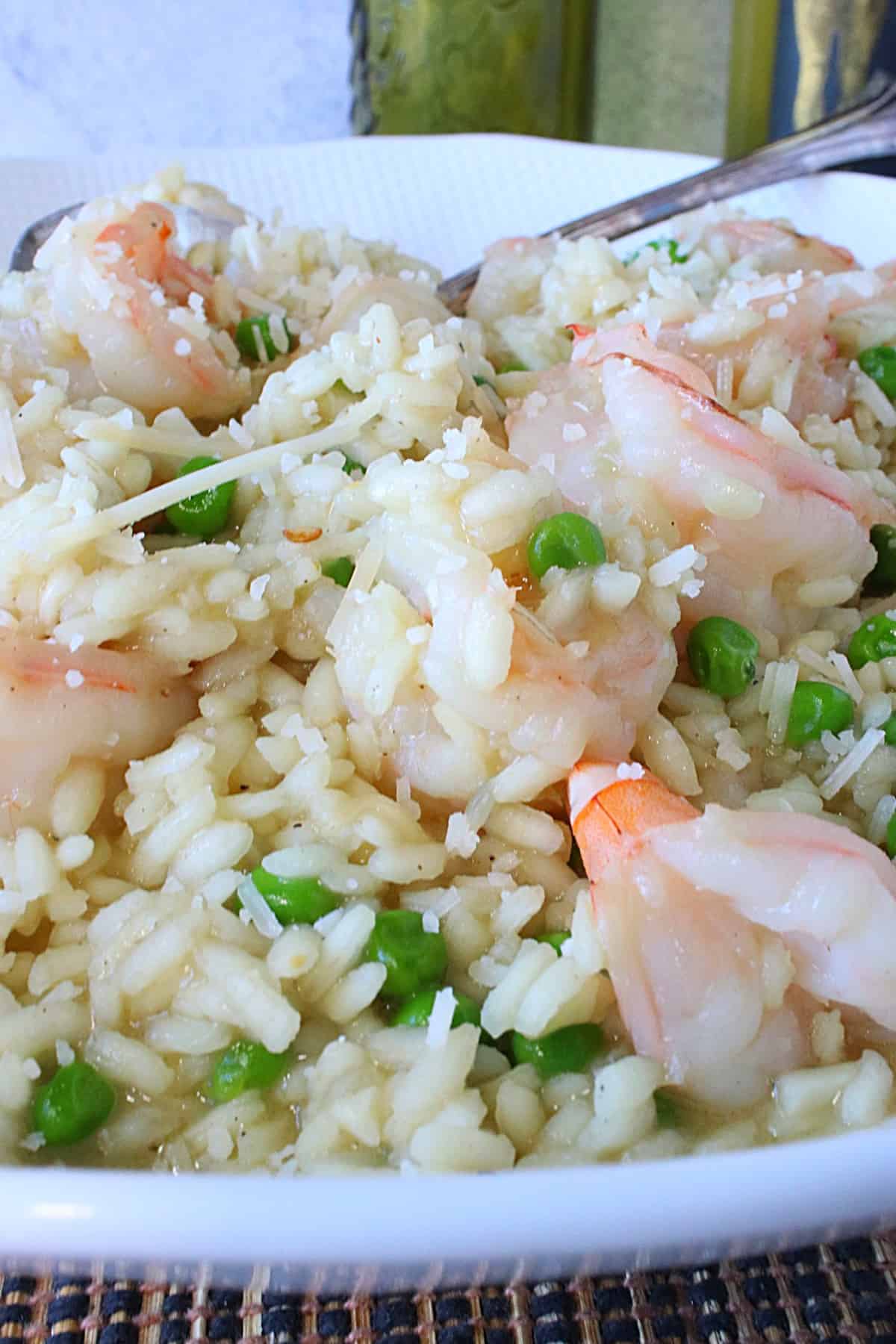 A white bowl filled with creamy Shrimp Scampi Risotto with peas and Parmesan.