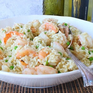 A delicious looking Shrimp Scampi Risotto with Wine and Parmesan in a white bowl with a serving spoon.