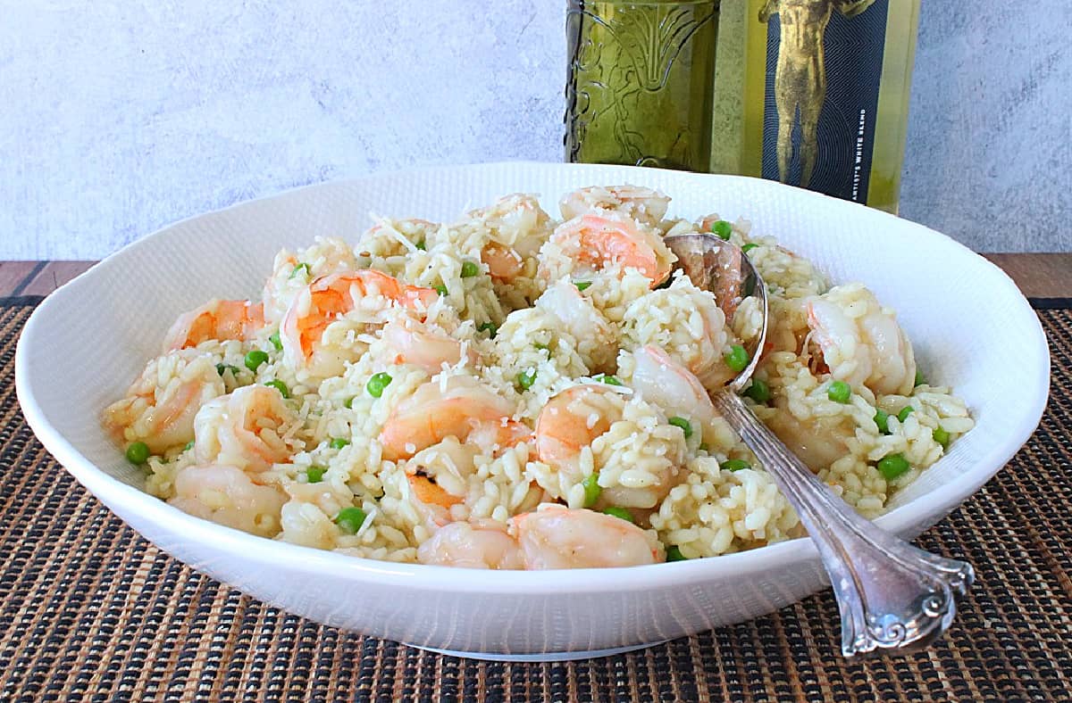A white bowl filled with a family portion of Shrimp Scampi Risotto with white wine and Parmesan along with a spoon.