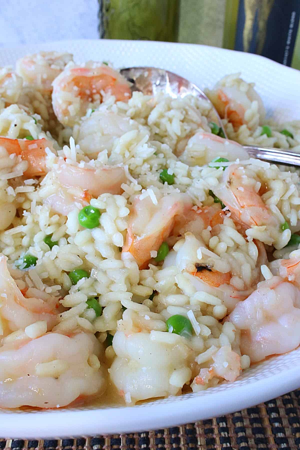 A large white bowl filled with creamy Shrimp Scampi Risotto with White Wine, Parmesan cheese, and peas.