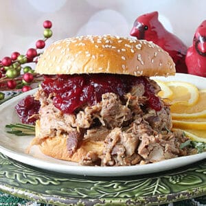 A Slow Cooker Cranberry Pulled Pork Sandwich with a bun and cranberry sauce.