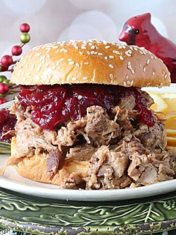 A Slow Cooker Cranberry Pulled Pork Sandwich with a bun and cranberry sauce.