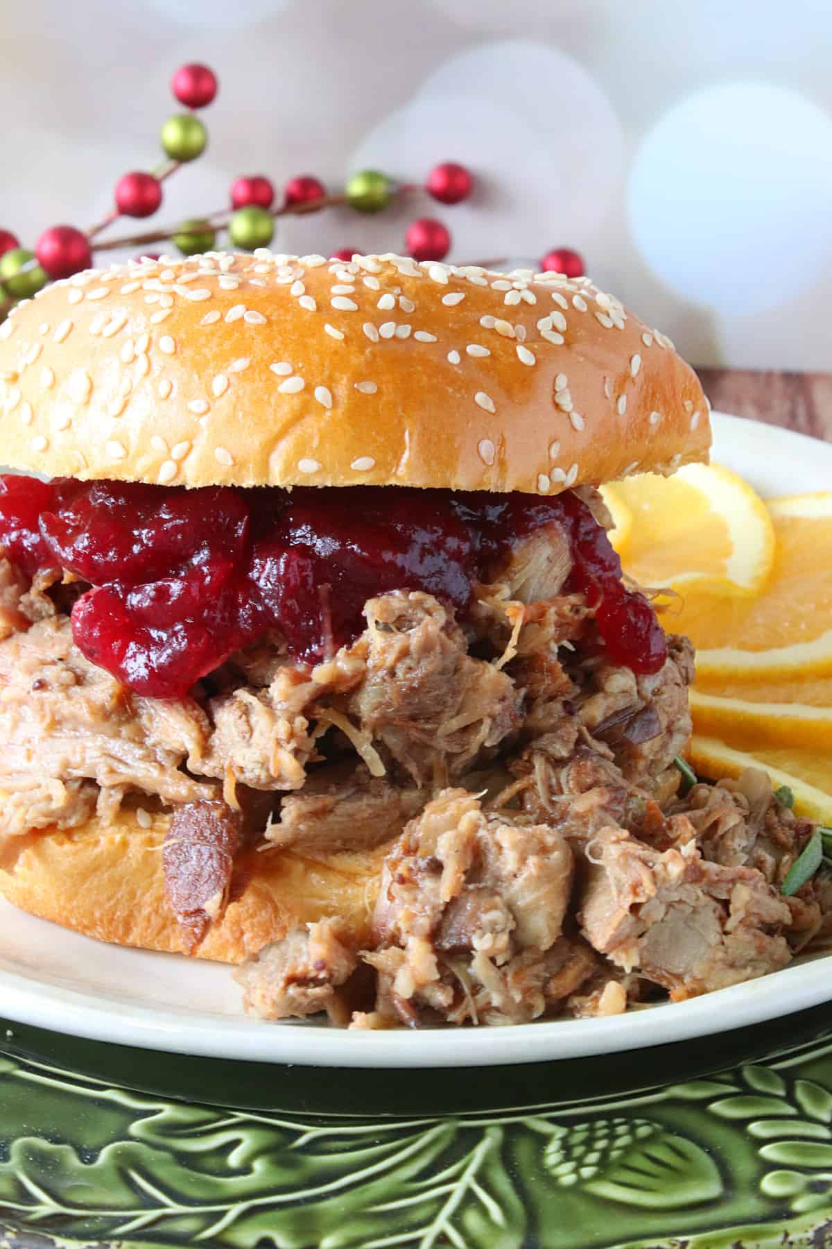 A Slow Cooker Cranberry Pulled Pork Sandwich piled high with meat and topped with a bun.