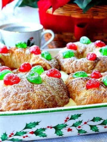 A pretty Christmas baking dish with holly and berries filled with Eggnog Pastry Cream Croissants.