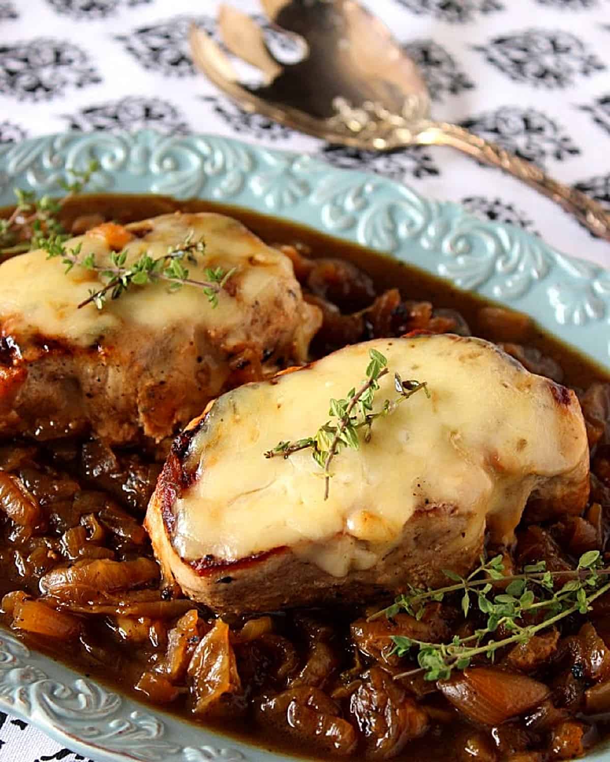 A plate of French Onion Pork chops sitting on top of a bed of properly caramelized onions.