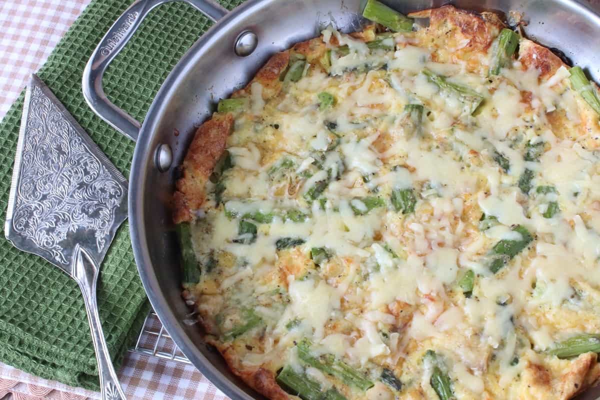 A silver skillet filled with a baked Asparagus and Gruyere Cheese Skillet Popover.