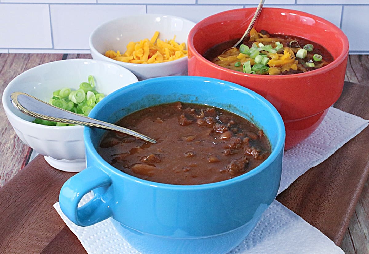 An orange and blue soup bowl each filled with Baked Bean Soup with Beef and Bacon.