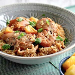 A blue serving bowl filled with Hawaiian Pineapple Chicken Thighs with parsley on top.