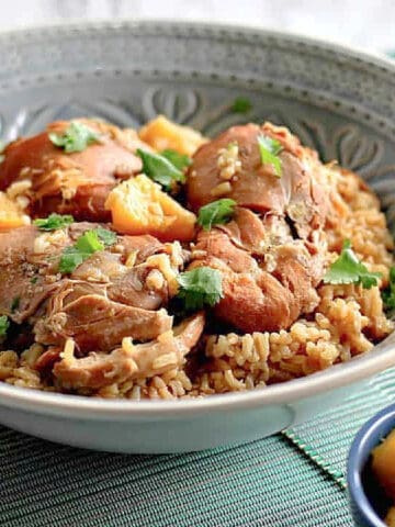 A blue serving bowl filled with Hawaiian Pineapple Chicken Thighs with parsley on top.