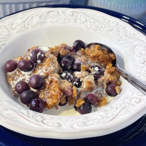 A white bowl filled with a serving of baked peanut butter and jelly oatmeal along with a spoon.