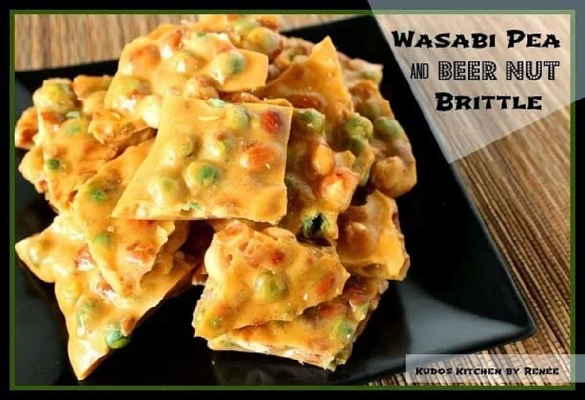 Wasabi Pea and Beer Nut Brittle A square black plate with Wasabi Pea and Beer Nut Brittle stacked on it.
