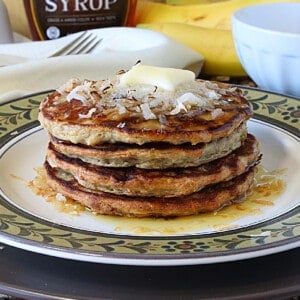 A stack of Oatmeal Pancakes topped with coconut and butter.