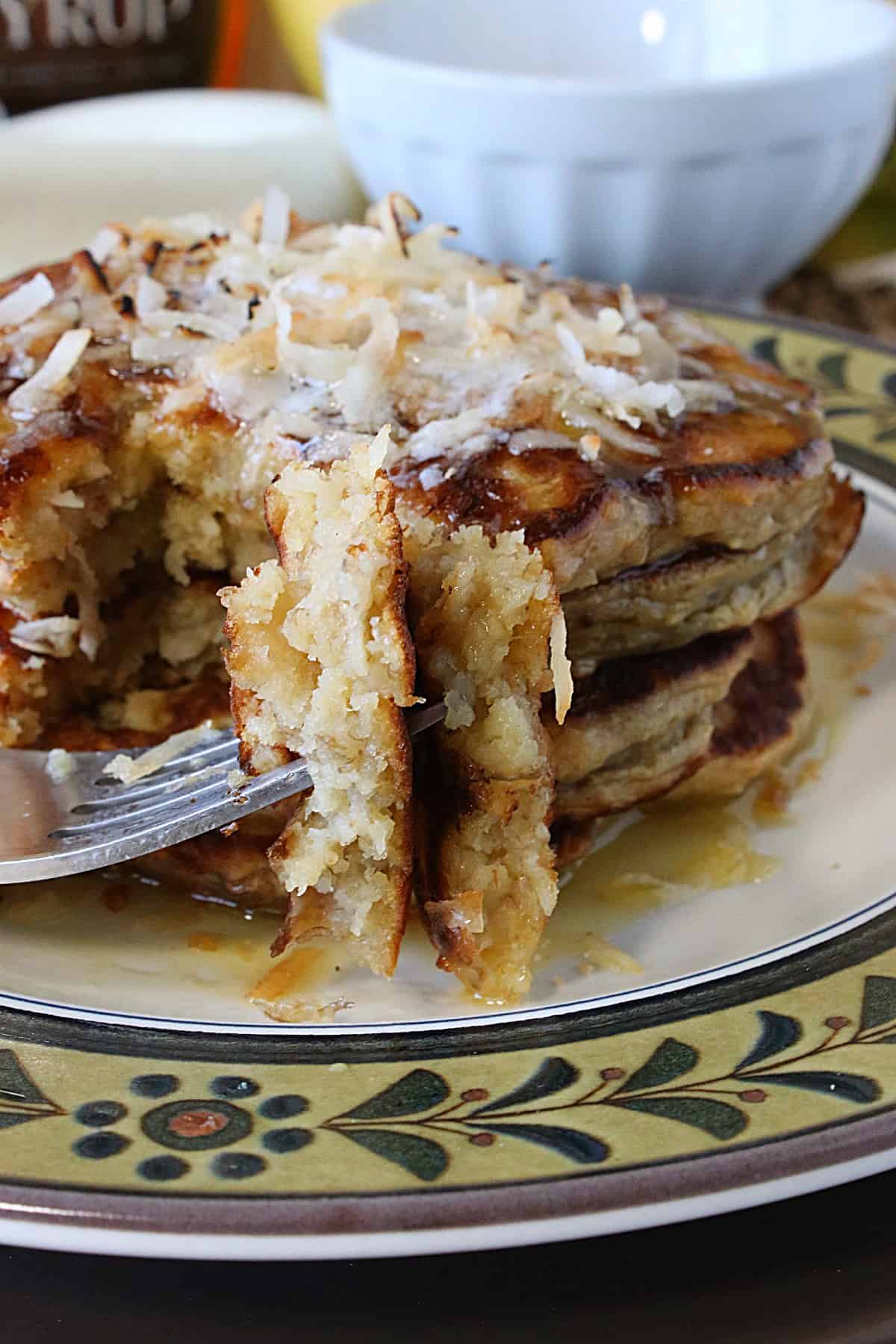 A fork with a bite of Oatmeal Pancakes with Banana and Coconut.