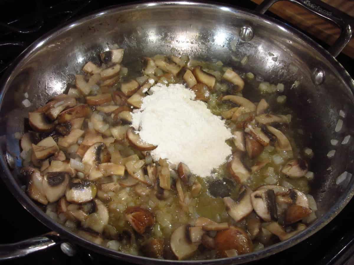 Flour and mushrooms in a skillet.