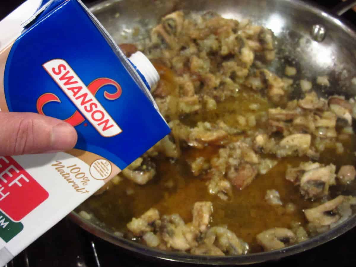 Beef stock being added to mushroom gravy.